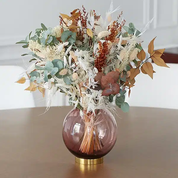 Bouquet de fleurs séchées dans un vase, posé sur une table.
