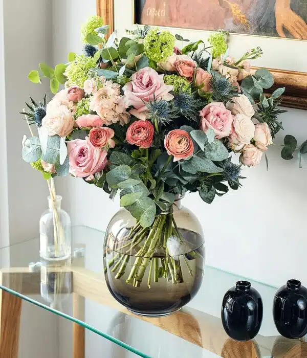bouquet de roses rose, roses branchues crème, chardons bleus, renoncules corail, viburnum verts, giroflées crème et eucalyptus